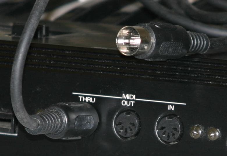 MIDI IN, OUT and THRU sockets on a synthesizer, with a 5-pin DIN cable